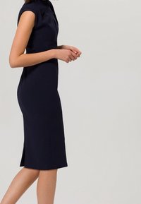 Marinblå klänning med korta ärmar, en hög halsringning och en sidofick, tillverkad av ett mjukt tyg med en slank silhuett.