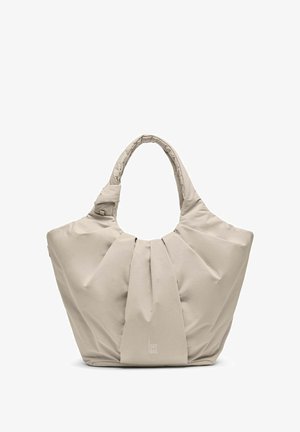 Sac fourre-tout en tissu beige doux avec poignée rembourrée, design plissé à l'avant et logo discret "GOT BAG" en bas au centre.