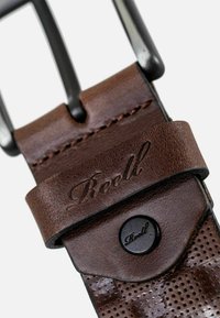 Brauner Ledergürtel mit durchbrochenem Design, eingeprägtem "Reell"-Logo, schwarzem Metallverschluss und Druckknopfverschluss-Detail. Glatte Textur und abgerundete Kanten.