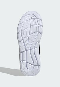Biela športová obuv s podrážkou, ktorá má textúrované vzory pre lepšiu priľnavosť a flexibilitu, s hladkým povrchom a tvarovanými akcentmi.