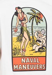 Hvid t-shirt med et farverigt vintage-print af en hula danser og en sømand, med teksten "NAVAL MANEUVERS" nederst.