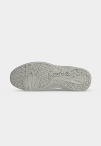 Σόλα παπουτσιού Reebok σε ανοιχτό γκρι χρώμα με ανάγλυφο μοτίβο πρόσκρουσης και το λογότυπο Reebok στο κέντρο της σόλας σε λευκό φόντο.
