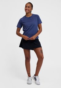 Niebieska, krótko rękawowa koszulka sportowa z okrągłym dekoltem, w zestawie z czarną spódnicą szortami. Uzupełniona białymi butami sportowymi z niebieskimi akcentami.