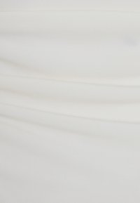 Vit tyg med en slät, stretchig textur som har subtila veckdetaljer. Materialet verkar lätt och något reflekterande.