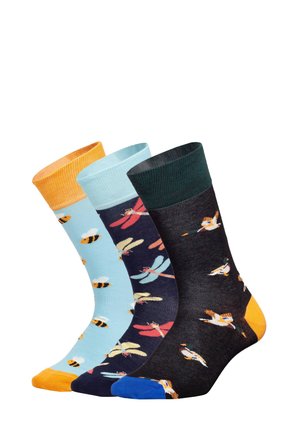 Tre par sokker: lyseblå med bier, marineblå med guldsmede, mørkegrå med fugle. Forskellige farver og mønstre med kontrastfarvede manchetter.