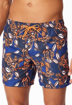 Mittlerer Bereich trägt blaue Badeshorts mit orangefarbenem Blumenmuster und orangefarbener Kordel, die an der Taille gebunden ist.
