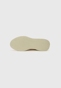 Schuhsohle in hellem Beige mit strukturiertem Oberflächen, leicht gewölbter Form und abgerundetem Zehenbereich. Verfügt über eine glatte Oberfläche und ein minimales Design.