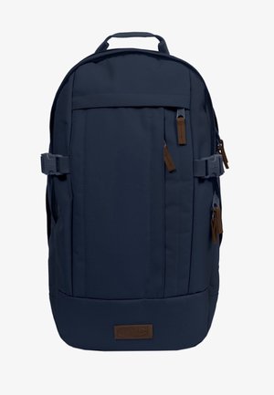 Mochila azul oscuro con múltiples compartimentos con cremallera, correas laterales de compresión, una asa superior y tiradores de cremallera marrones, además de una etiqueta con el logotipo.