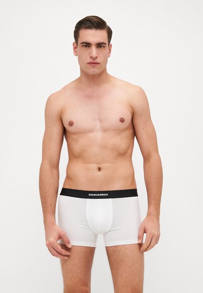 Boxer-briefs blancs avec une ceinture élastique noire arborant le logo "DSQUARED2." Le matériau semble lisse avec un design ajusté.