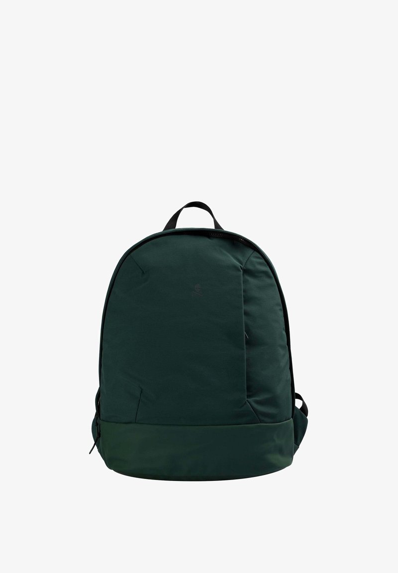 Mochila de tela verde oscura con una textura suave, forma redondeada, asa superior y correas de hombro acolchadas. Presenta un diseño minimalista.