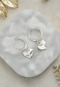 Silver hoops med en vriden design, varje prydd med en hängande hjärtan charm med en texturerad yta.