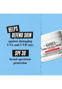 Hvit krukke med Kiehl's Ultra Facial Cream med svart tekst på blå bakgrunn, som nevner SPF 30 og beskyttelse mot UVA- og UVB-stråler.