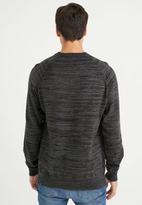 Suéter gris oscuro con un patrón texturizado jaspeado, cuello redondo, puños y dobladillo de canalé. Presenta mangas raglán para un ajuste relajado.