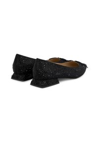 Schwarze Ballerinas mit strukturiertem Überzug, ausgestattet mit einem niedrigen Blockabsatz und dekorativen Details. Das Material hat ein Muster aus kleinen Aussparungen.