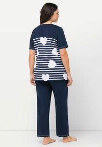 Námořnický bavlněný pyžamový set obsahující vršek s krátkým rukávem s bílými srdíčky na pruhovaném pozadí a odpovídající kalhoty.