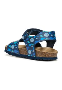 Sandali navy con motivo pesci in azzurro chiaro e verde acqua, dotati di una soletta in sughero, cinturino regolabile e suola a zigzag per una migliore aderenza.