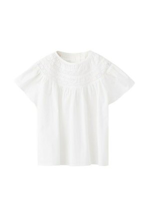 Blouse en coton blanc à manches courtes avec un empiècement brodé complexe autour de l'encolure ronde.