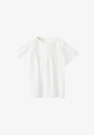 Blouse en coton blanc à manches courtes avec un empiècement brodé complexe autour de l'encolure ronde.