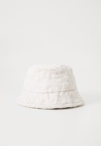Hvit faux fur bøttehatt med en myk, teksturert overflate, som har en bred, fleksibel brem og en strukturert sylinderform.