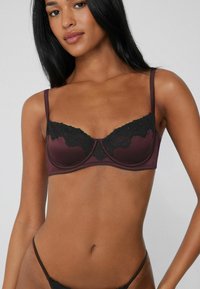 Marlot burgundy bra with black lace trim, underwire support, adjustable straps, smooth fabric, and scalloped edges.