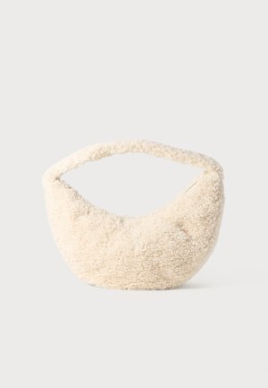 Sac de couleur crème avec une texture douce et duveteuse. Forme courbée et large sangle pour le porter. Design simple, sans matériel ou accents visibles.
