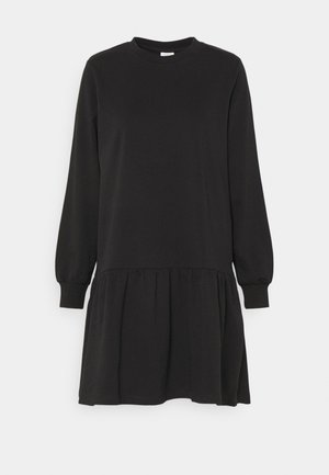 Czarna sukienka z długim rękawem, dekoltem okrągłym i szczegółem marszczonej spódnicy, przedstawiona na jednolitym jasnym tle.