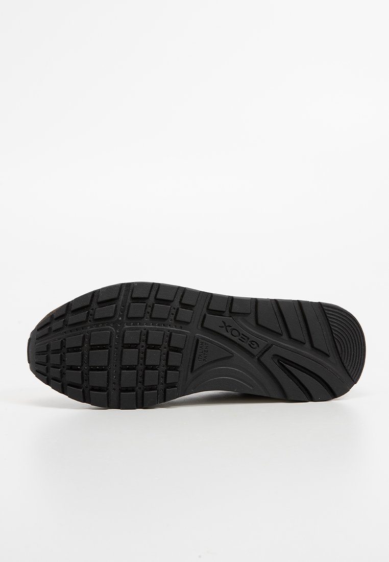 Schwarze Sneaker-Sohle mit strukturiertem Muster, hervorgehobenen Kerben und Profil für besseren Grip, geprägtes Logo-Detail an der Seite.