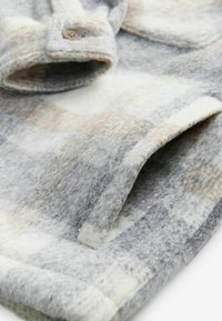 Sivá a biela fleece tkanina so vzorom, s jemným, textúrovaným povrchom, so zapínaním na gombík a preloženým golierom.