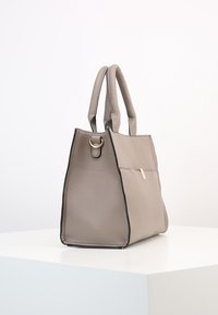Borsa tote grigia in pelle con un design strutturato, superficie testurizzata, doppio manico e un accento oro sulla parte anteriore. Presenta rifiniture nere.