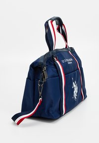 Borsa sportiva blu navy con manici a strisce bianche e rosse, chiusura con cerniera e un logo con un giocatore di polo sul lato. Realizzata in tessuto resistente.