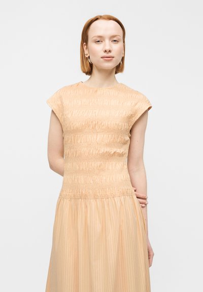 Φόρεμα σε απόχρωση ροδάκινου με υφή και σφηκάτη κορυφή και πλισέ φούστα. Κοντά μανίκια καπέλο και ελαστική μέση που ενισχύουν την άνεση και την εφαρμογή.