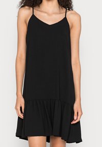 Czarna sukienka bez rękawów z dekoltem w kształcie litery V, z falbaną na dole. Wykonana z miękkiego materiału w luźnym, komfortowym fasonie. Regulowane cienkie ramiączka.