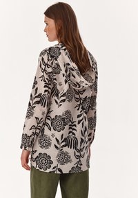 Felpa con maniche lunghe in tessuto beige con motivi floreali neri e cappuccio regolabile. Vestibilità comoda con polsini con bottoni e spacchi laterali.