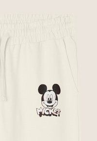 Pantaloni di cotone bianchi con vita elasticizzata. Presentano una grafica stampata di Mickey Mouse in nero e la parola "MICKEY" in un carattere in grassetto.