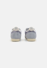 Sneaker in suede grigio con tomaia in rete decorata, dotate di una suola in gomma color crema e un logo blu chiaro sul tallone.