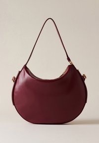 Borsa a tracolla in pelle bordeaux a forma di mezzaluna, con bordi arrotondati e una singola tracolla. Presenta un accento in metallo dorato.
