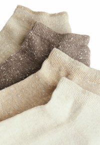 Kniestrümpfe in Creme, Beige und Hellbraun mit einer gesprenkelten Textur und gerippten Bündchen. Weiches, gestricktes Material mit subtilen Farbvariationen.