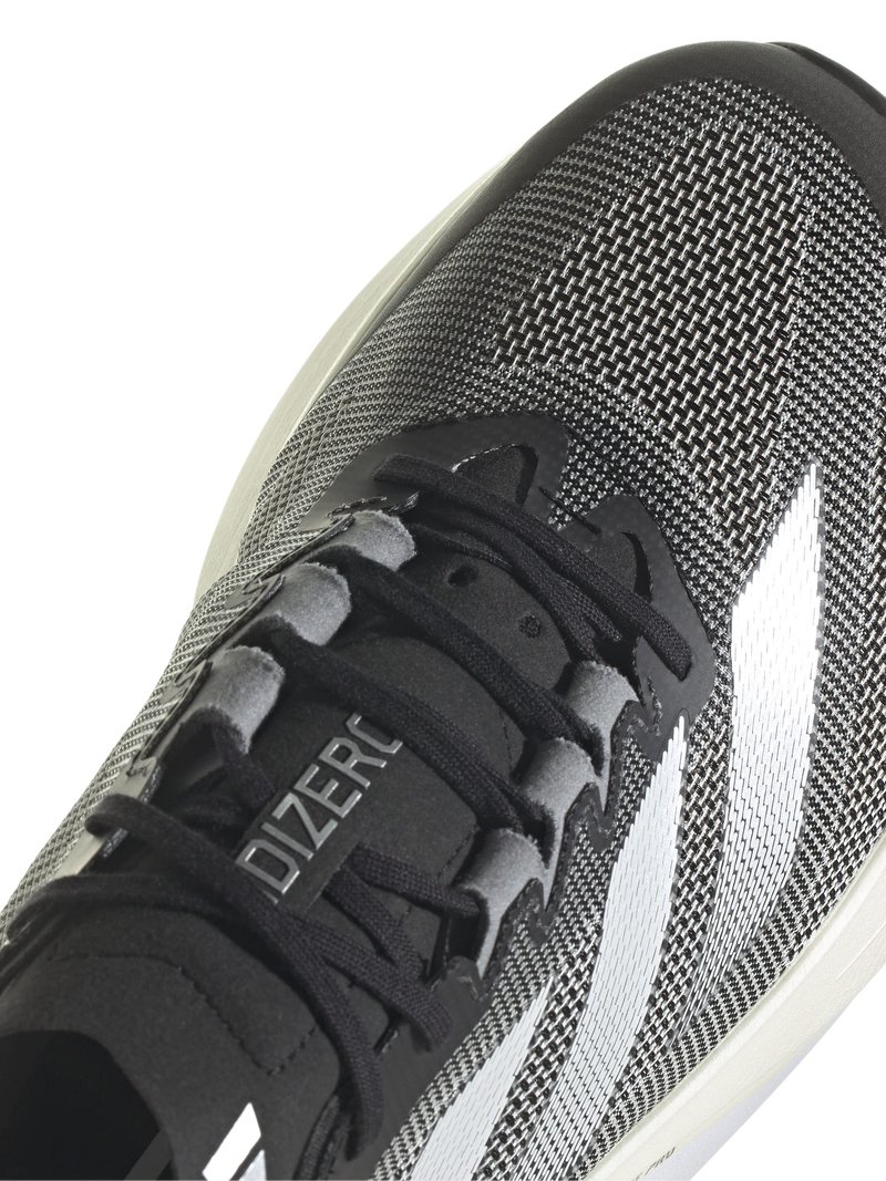 Chaussure de sport noire et grise avec une tige en mesh texturé, des rayures blanches et des lacets noirs. Dotée d'une semelle rembourrée pour un confort optimal.