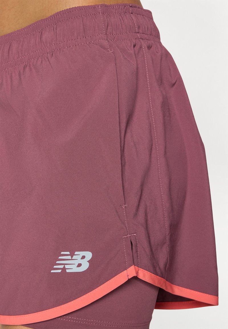 Shorts atléticos cortos en un color mauve oscuro con un ribete coral en contraste. Fabricados en un tejido ligero, con una cintura elástica y un logo.