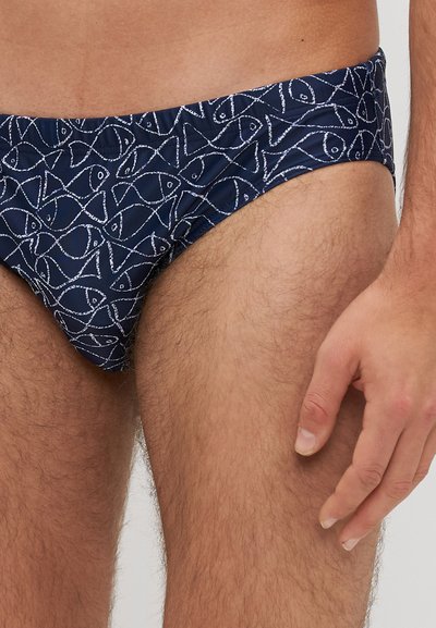 Marine zwembroek met een wit vispatroon, voorzien van een laag uitgesneden ontwerp en een gladde, rekbare stof. Geaccentueerd bij de tailleband.