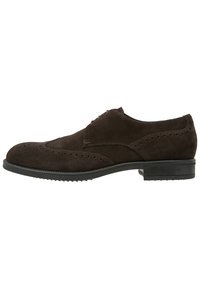 Chaussure habillée en daim marron avec des détails brogués, présentant un design à lacets et une semelle en caoutchouc texturée pour la traction et la durabilité.