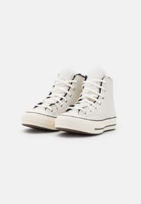 Höga sneakers i kräm och grått med texturläder, plyschvit foder, svarta accenter och en gummisul med randig detalj.