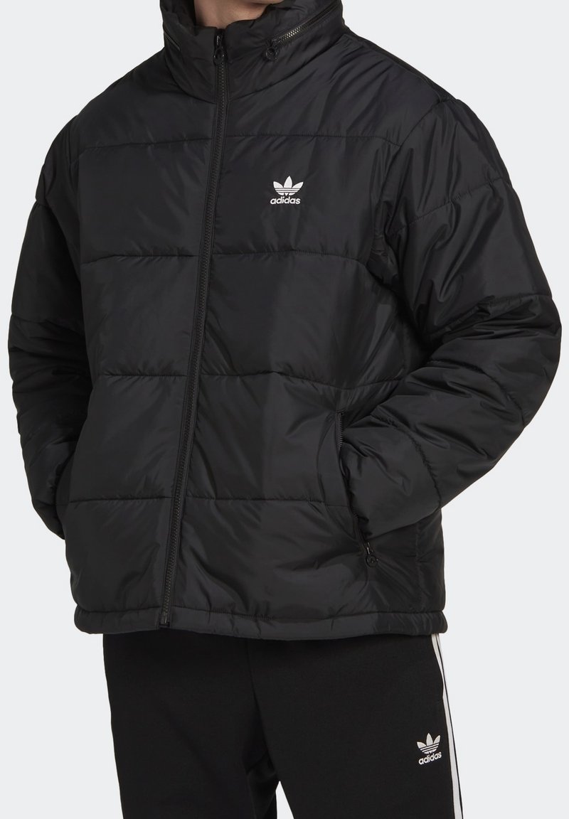 Czarna kurtka puchowa z wysokim kołnierzem, z poziomymi pikowanymi sekcjami, kieszeniami na zamek i białym logo Adidas na lewej piersi.