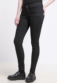 Sorte skinny jeans laget av denim, med en glatt tekstur, klassisk fem-lomme design, og solid knapp- og glidelås-lukking.