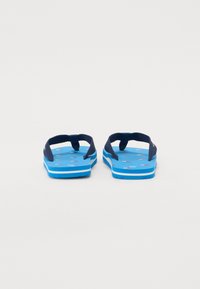 Blå flip-flops med marineblå stropper, med en teksturert fotseng med et mønster av små fargerike grafikker, og en hvit stripet såle.