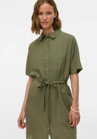 Abito camicia verde oliva con maniche corte, bottoni frontali e vita legata. Tessuto morbido e dettagli sul colletto. Design semplice.