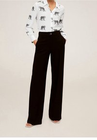 Chemise blanche à imprimé léopard noir, de conception à boutons, associée à un pantalon large noir à taille haute. Tissu lisse, manches longues, poches.