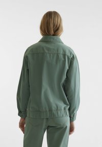 Veste décontractée verte en tissu léger, dotée d'une coupe décontractée, de poignets élastiqués et d'un simple col.