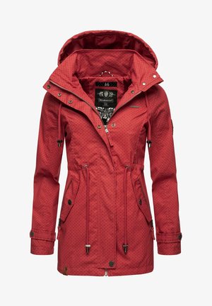 Punainen vedenpitävä takki, jossa on mustia pilkkuja, kiristysnyörivyötärö ja huppu. Varusteena vetoketju- ja nepparisäätö sekä kaksi sivutaskua.