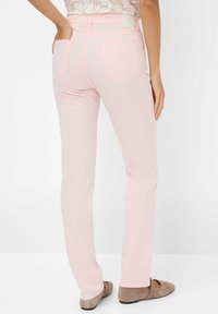 Lichtroze skinny jeans met een gladde textuur, twee achterzakken en een taillebandlabel. Gecombineerd met plat, tankleurige balletachtige schoenen.